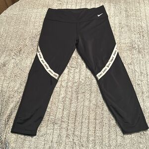 Black Nike active wear workout pants. With white store along the knee says Nike